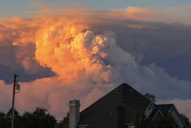 A massive pyrocumulus cloud rises from the Park Fire, with rooftops of Chico in the foreground.