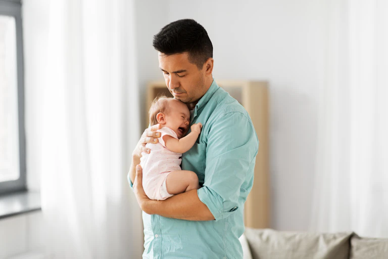 A man holding a crying baby.