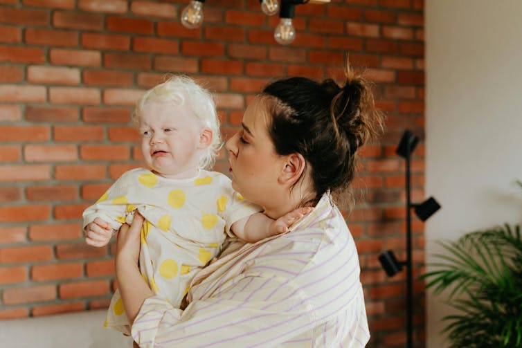 A woman holding a small child who is crying.