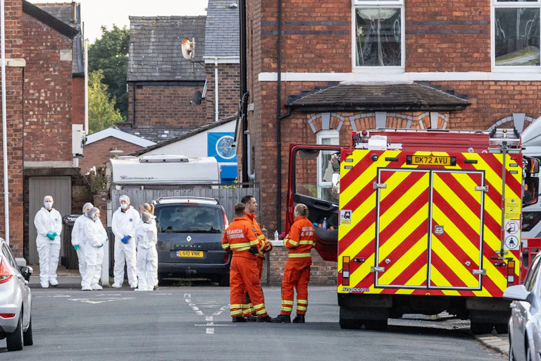 Emergency services and responders in white protective suits in a road.