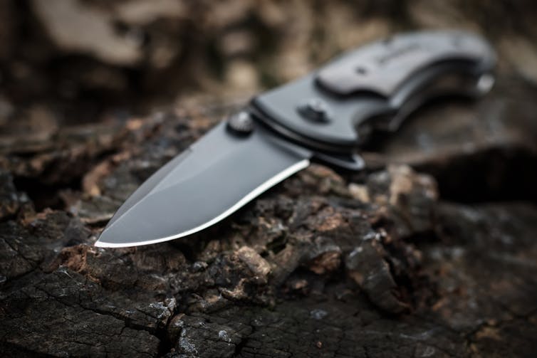 Faca dobrável em um tronco de madeira