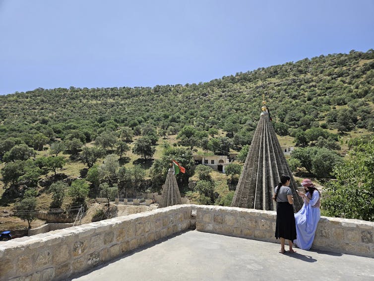 Two women standing outside a holy Yazidi temple.
