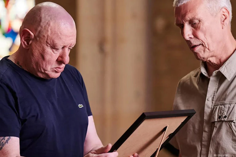 Shaun Ryder looks at a picture with bandmate Bez.