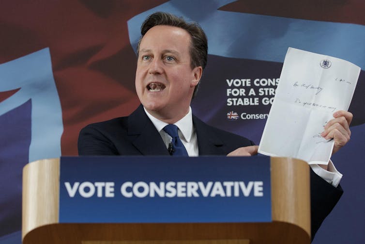 David Cameron holding up and pointing to a letter with Treasury branding/