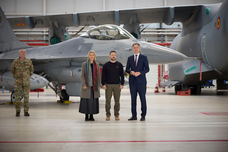 Ukrainian President Volodymyr Zelenskyy, center, stand with Belgian Prime Minister Alexander De Croo, right, and Defence minister Ludivine Dedonder, in front of a F-16 fighter aircraft