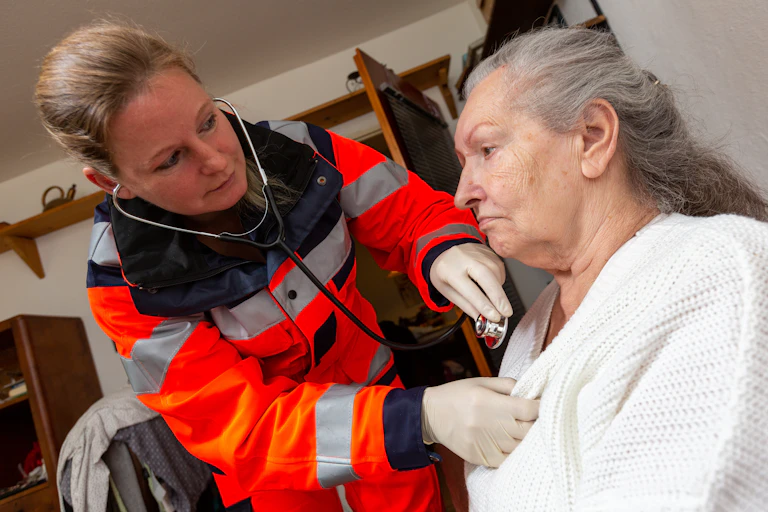 A woman paramedic listening to an older woman's heart with a stethoscope