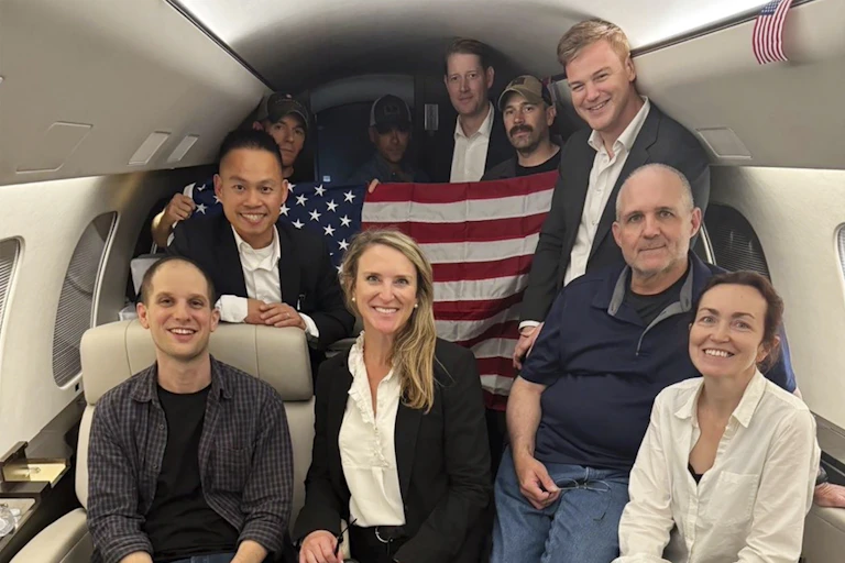A group of people in a private jet holding an American flag