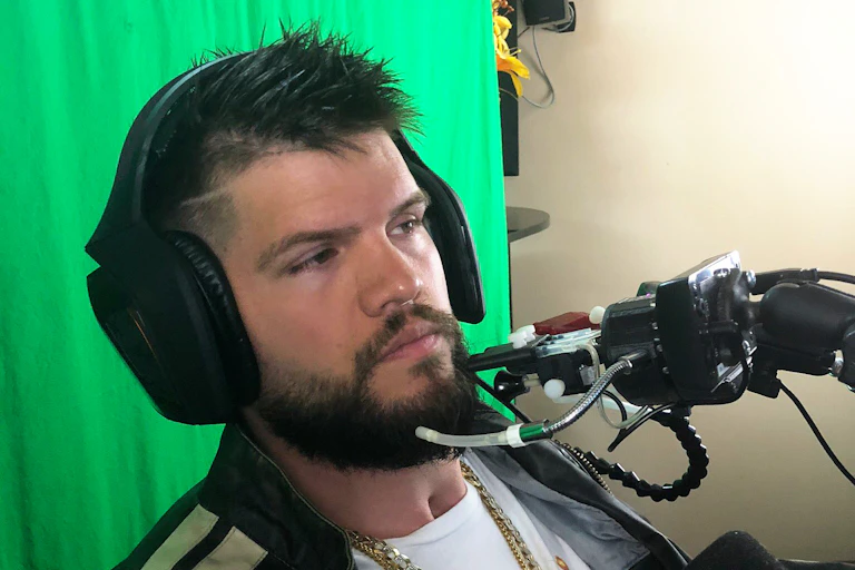 a man wearing headphones sits with a set of tubes in front of his mouth