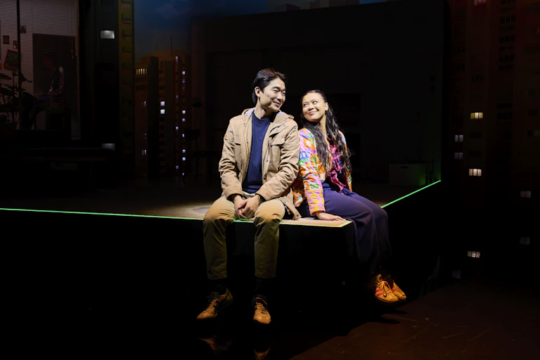 A man and woman sit on a stage