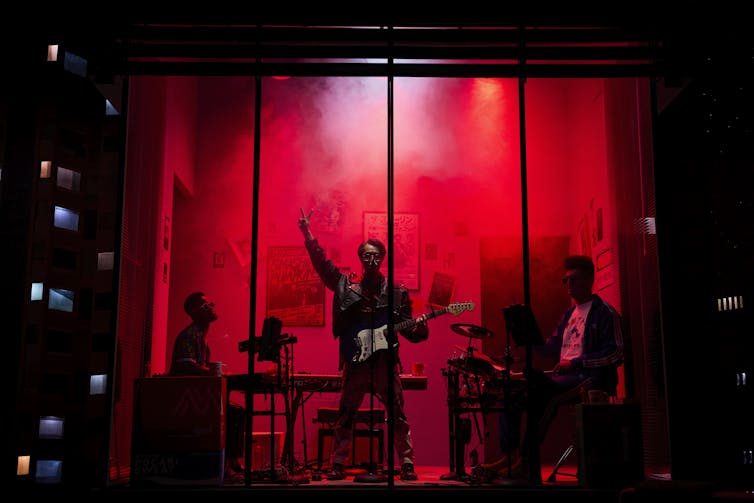 A band in a red-lit apartment.