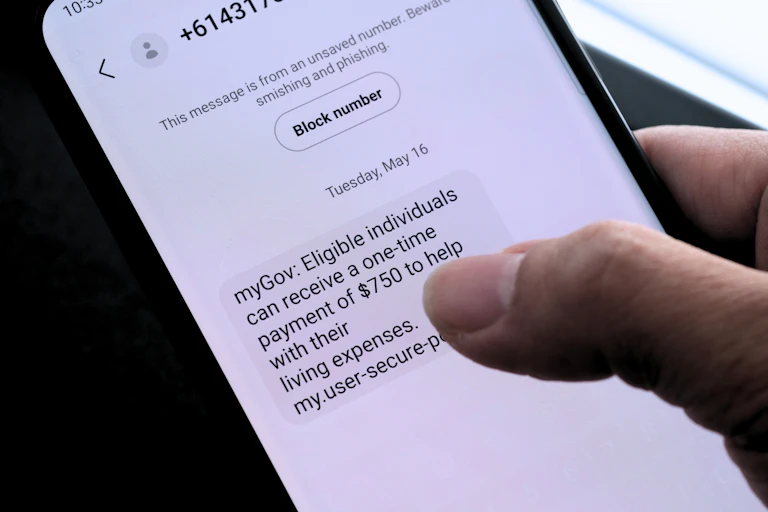 A person reading a text that advises them of a fake myGov payment.