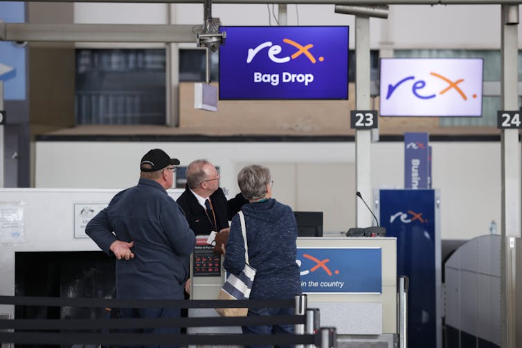 A man and a woman being served at an airline counter