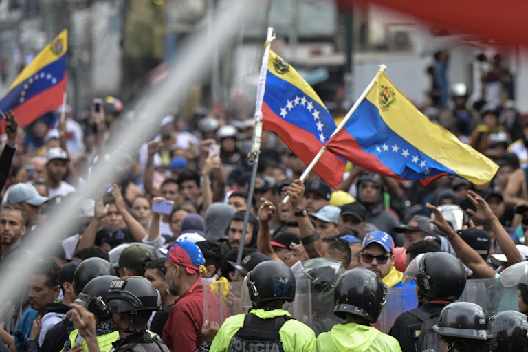 A group of protesters hold aloft flags while police look on.