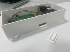 A white metal rectangular box about 16cm in length with wires and a green motherboard inside