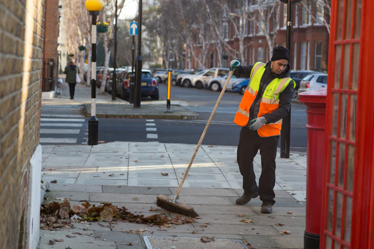A man sweeping leaves in the street