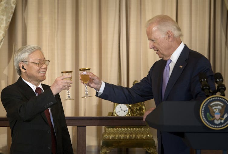 Two men in suits raise glasses.