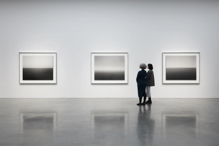 Two women look at photographs in a gallery