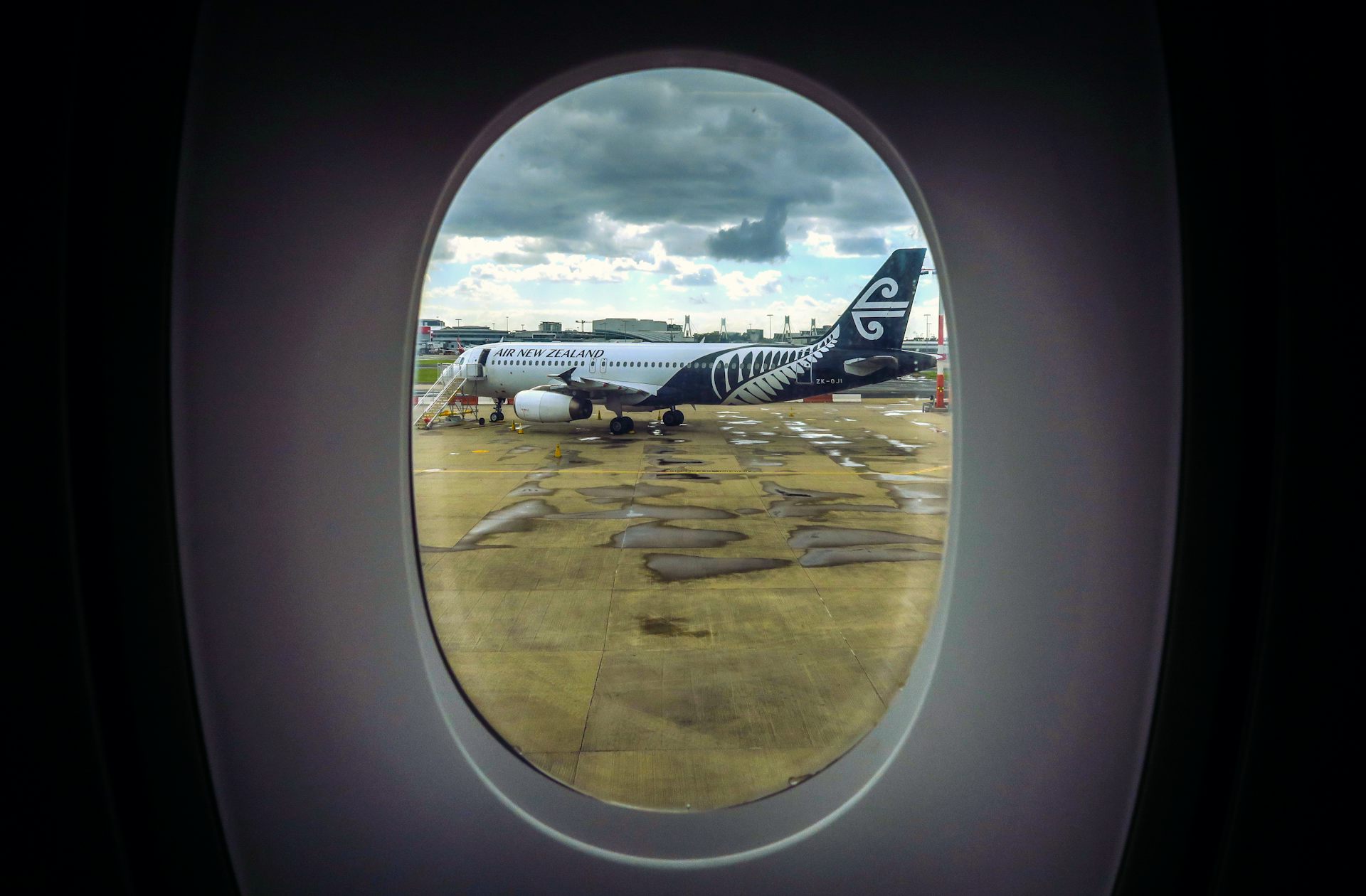 An Air New Zealand plane can be seen through the window of another plane as it sits on the tarmac at Auckland International Airpor