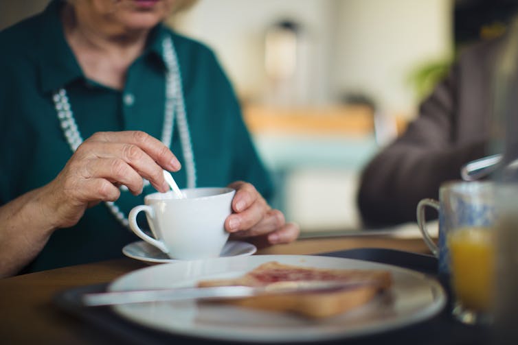 Aged care resident stirs her tea