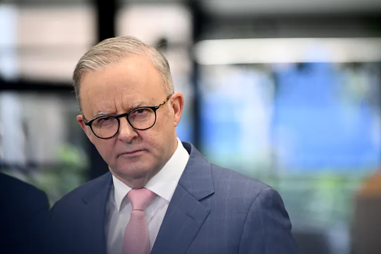 A man in a suit and glasses frowns