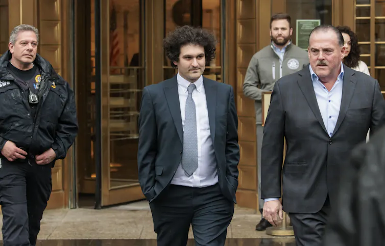 Sam Bankman-Fried accompanied by security staff as he leaves court.