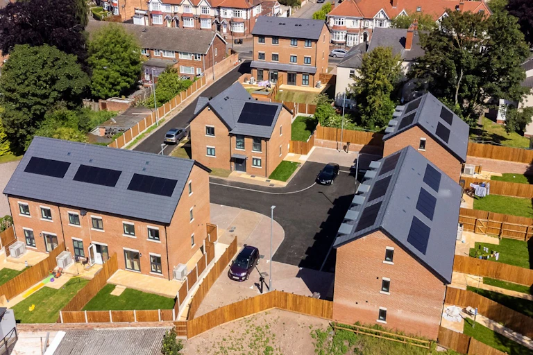 aerial shot of new homes with solar panels, gardens and trees