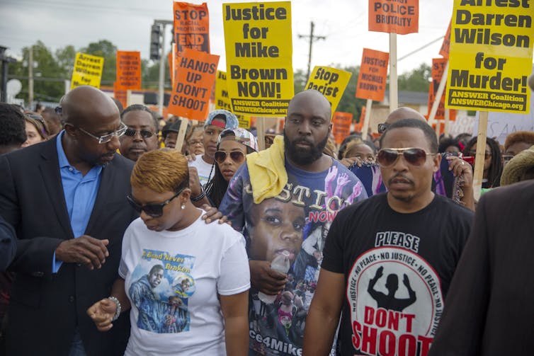 The parents of a Black teenager march in protest against a white police officer who shot and killed their son.