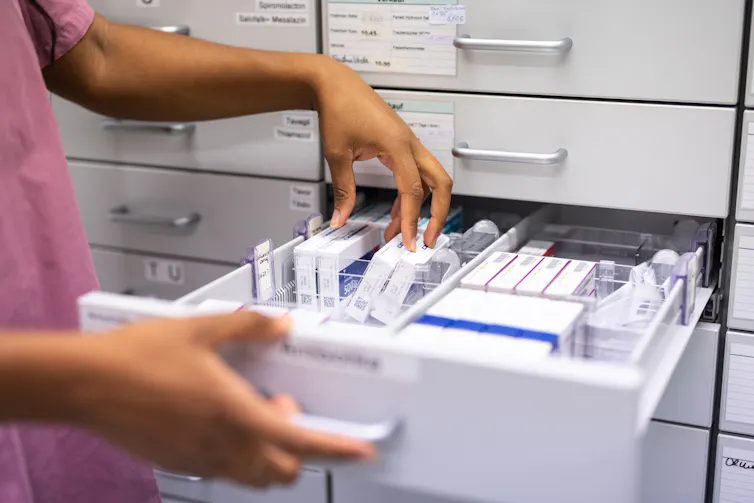 Pharmacist searching for prescription medicine in storage rack