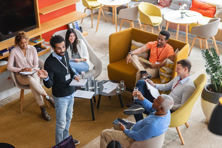 An overhead view of a group of diverse corporate employees meeting in a white-collar office setting.