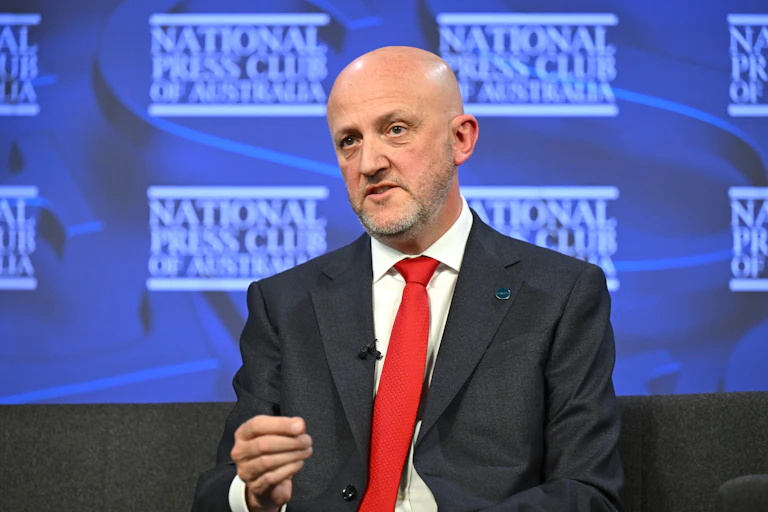 A man in a suit and red tie speaks