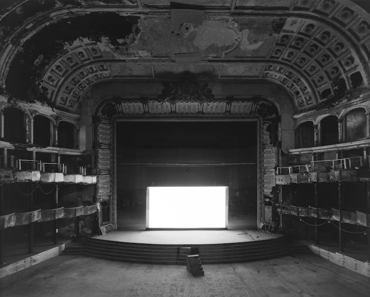 A dilapidated opera house with a bright white screen.