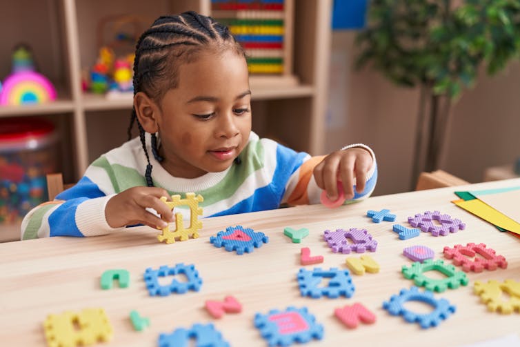 A boy plays with multicoloured puzzle tiles