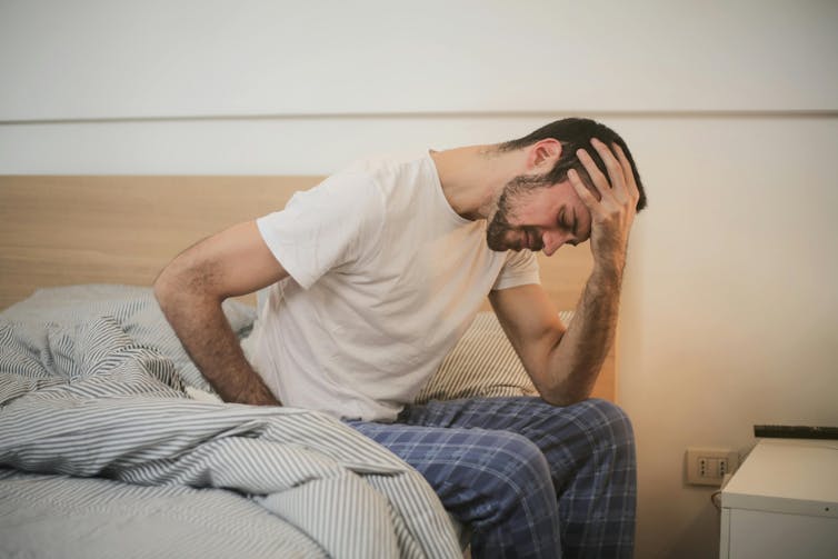 Man sits on the side of his bed