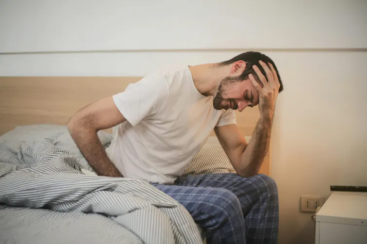 Man sits on the side of his bed