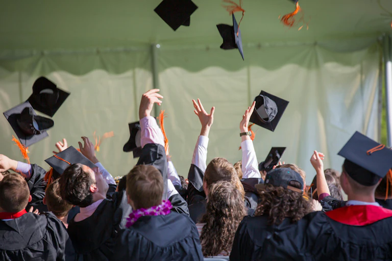 Graduates in caps and gown throw their caps in the air.