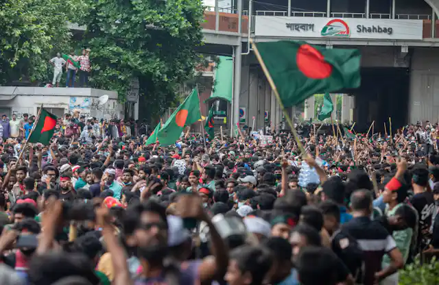 A crowd of people hold aloft green and red flags.
