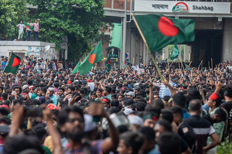 A crowd of people hold aloft green and red flags.