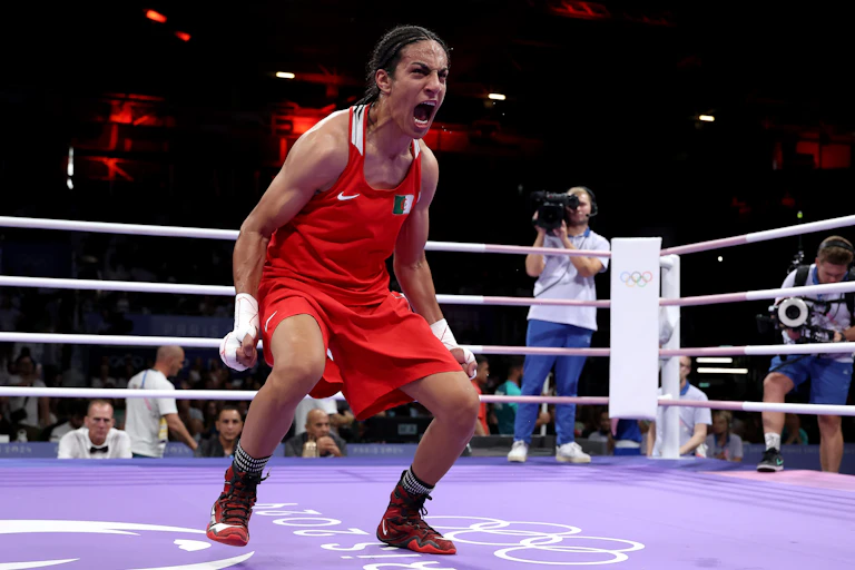 Female boxer dressed in red uniform screaming at the top of her lungs.