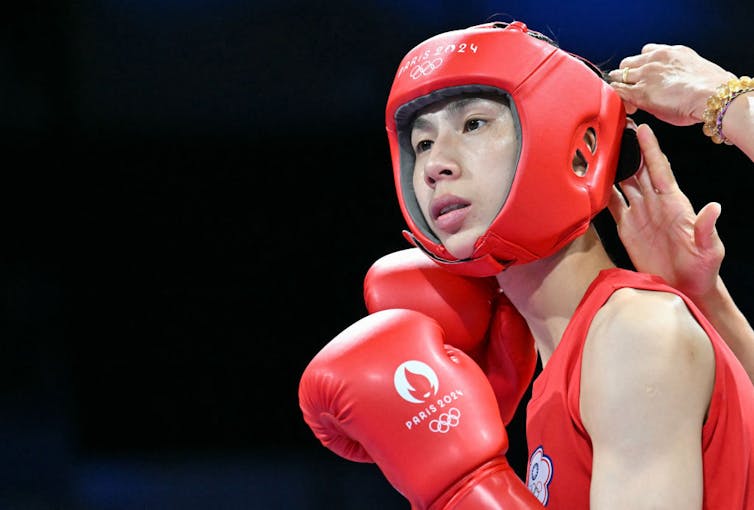 Young female boxer wearing red protective helmet and red gloves strikes a pose.