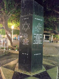 A black marble monument with engraved text on each side, and a six-sided star.