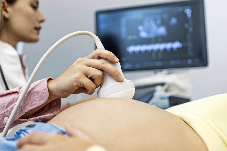 A doctor performing an ultrasound on a pregnant person.