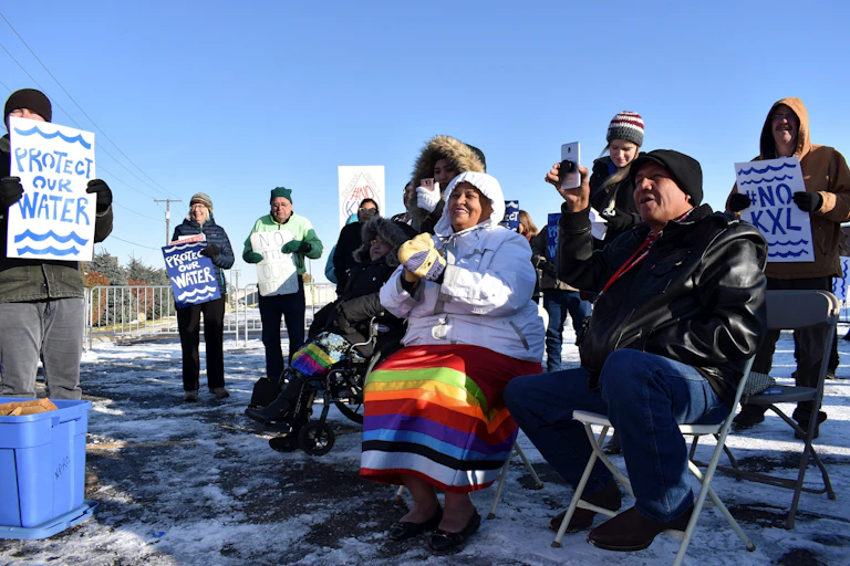 A group of people sit and stand holding signs.