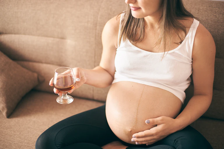 Pregnant female drinking cognac during pregnancy period.