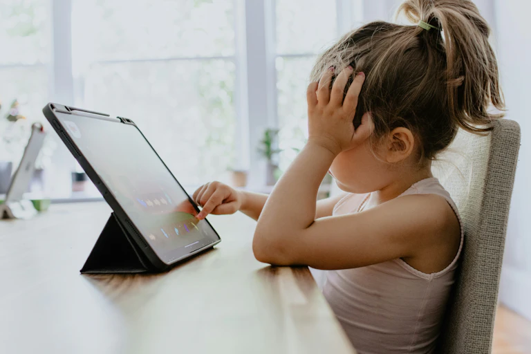 Girl uses a tablet at the kitchen table