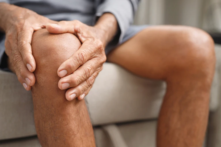 Man sitting on sofa clutching knee