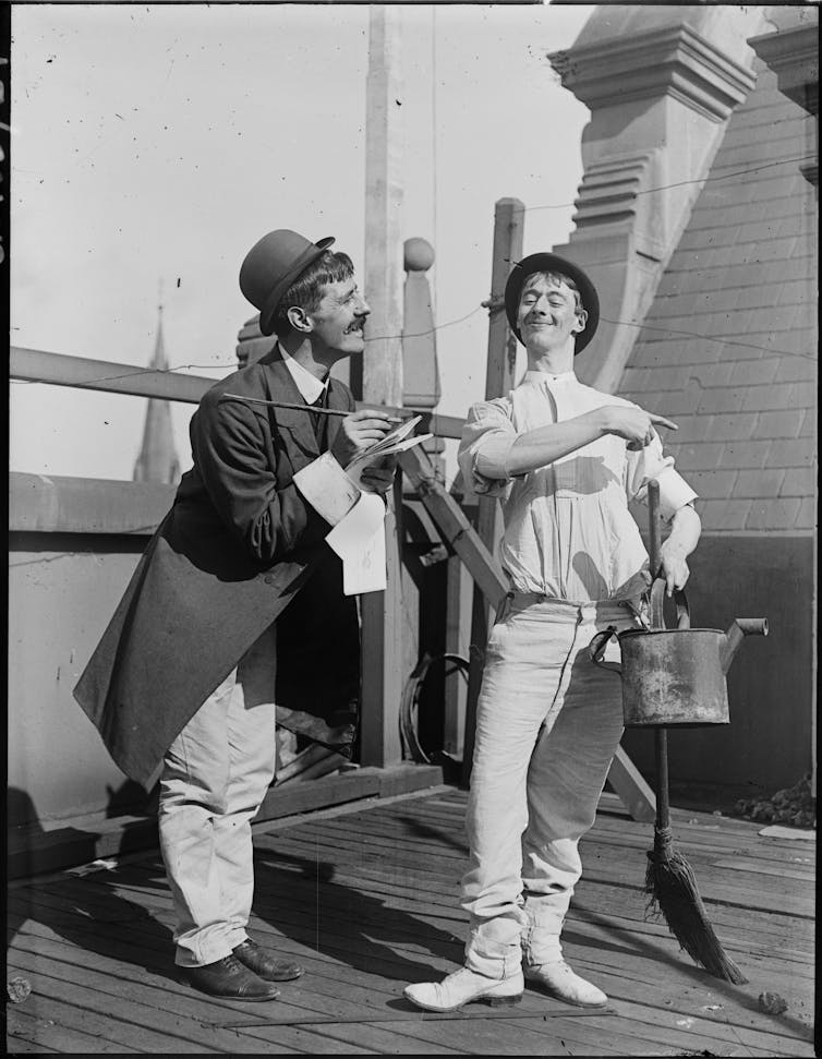 Black and white photograph, two men playing dress-ups.