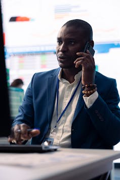 Businessman talks on phone while looking at a screen
