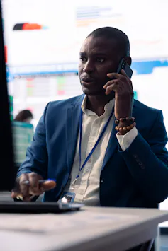 Businessman talks on phone while looking at a screen