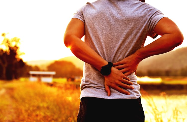 Man pauses from run to nurse lower back pain