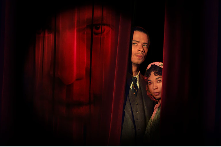 Two vampires behind a red curtain